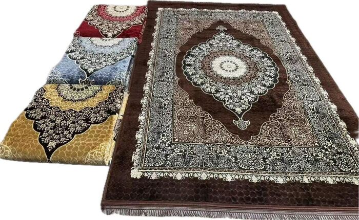 Brown medallion carpet alongside folded rugs in red, blue and gold