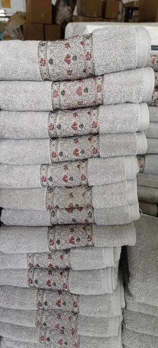 Stacked grey towels with patterned border, warehouse stock photo
